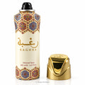 A 200 ml can of Raghba Perfumed Spray with a black spray nozzle, featuring a cream-colored body with gold Arabic calligraphy and a blue and gold geometric pattern near the top and bottom. The metallic gold cap is shown standing next to the can on a plain white background.