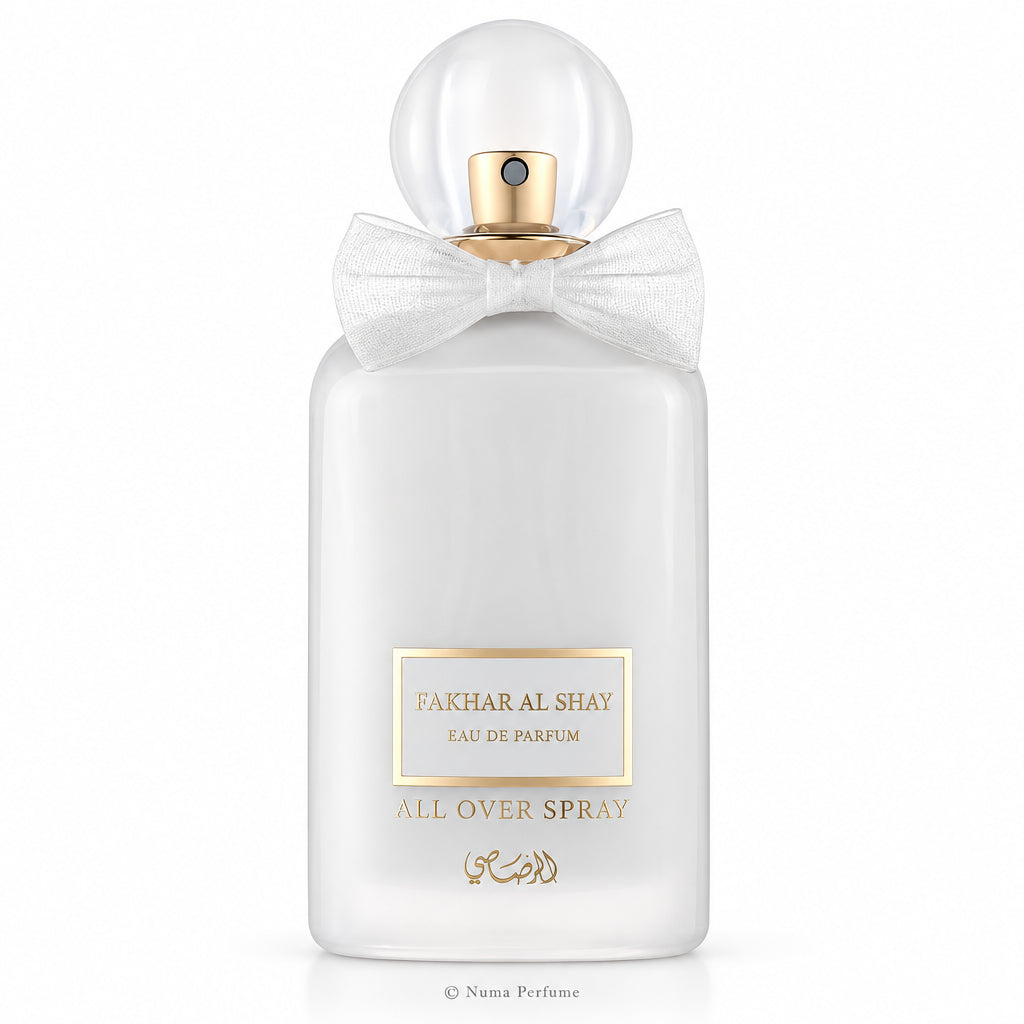 A frosted glass perfume bottle with a white satin bow around the neck, a gold spray mechanism, and a gold-bordered label that reads 'TAKHIL ALFA' and 'ALCOHOL-FREE ALL OVER SPRAY'.