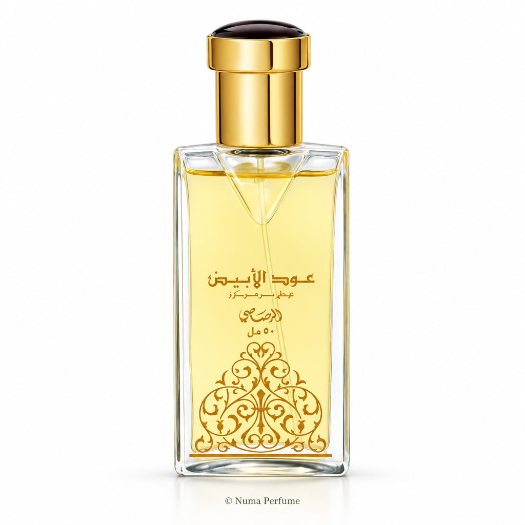 A rectangular glass perfume bottle filled with pale yellow liquid, featuring a shiny gold cap and gold Arabic lettering with an ornate gold pattern on the front, set against a plain white background.